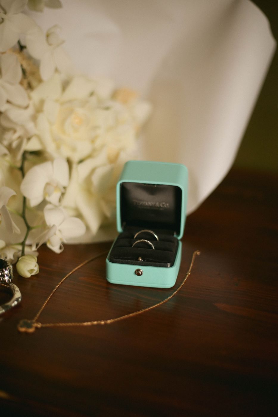 Engagement rings beside white orchids